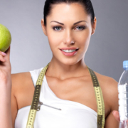 una giovane donna tiene in mano una mela e una bottiglia d'acqua