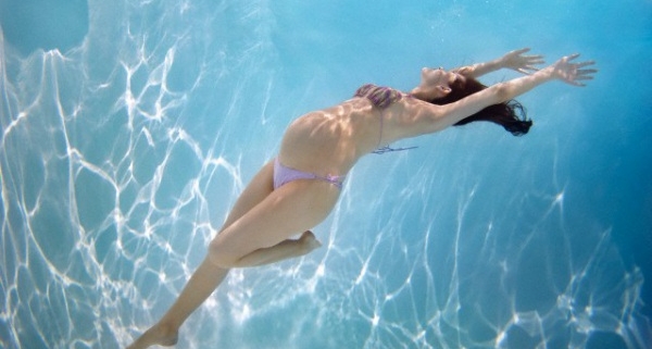 gravidanza, una donna con il pancione nuota in piscina