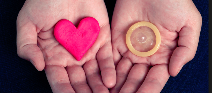 infezioni sessuali. aids/hiv. due palmi delle mani: uno contiene un preservativo, l'altro un cuore