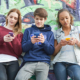 social: tre ragazzi con lo smartphone seduti su un muretto