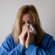 raffreddore: una donna si soffia il naso