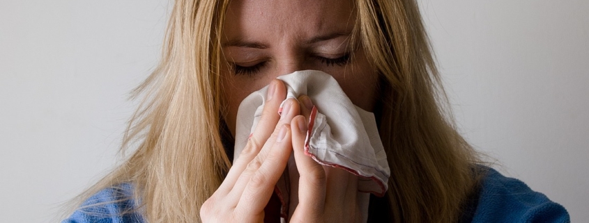 raffreddore: una donna si soffia il naso