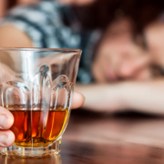 alcol, una ragazza con la testa appoggiata sul tavolo impugna un bicchiere di superalcolico