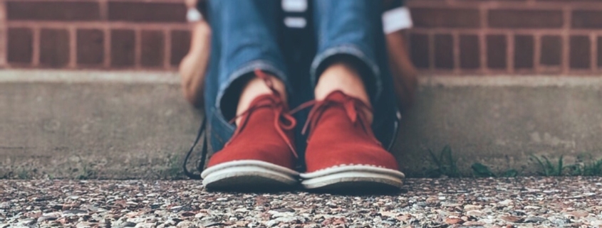social media: i piedi di un adolescente seduto sul marciapiede