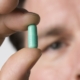 l’antibiotici: un uomo con una pillola tra le dita della mano
