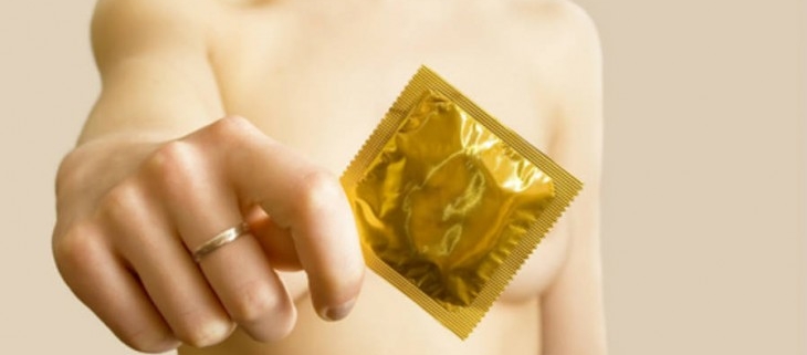 una donna mostra in primo piano un preservativo per prevenire le infezioni sessualmente trasmesse