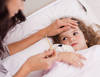 isindromi simil-influenzali, una bambina a letto mostra sintomi simil influenzali e la madre al suo capezzale le misura la febbre.