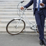tumori, un uomo in giacca e cravatta scrive al cellulare appoggiato ad una bici