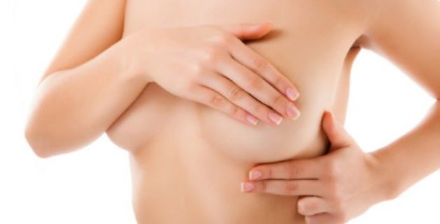 tumore al seno, il busto di una donna con una mano all'altezza della mammella