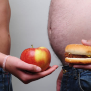 colesterolo, due uomini tengono in mano un panino e una mela