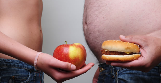 colesterolo, due uomini tengono in mano un panino e una mela