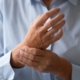 artrite reumatoide, un uomo si stringe il polso