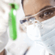 terapia genica, una dottoressa in laboratorio osservata provetta con all'interno un liquido verde