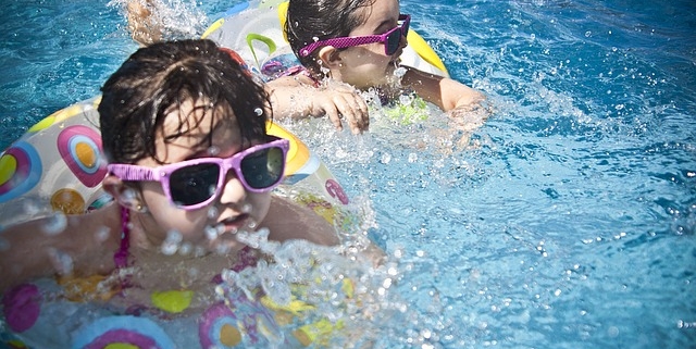 otite, due bimbi nuotano in piscina con gli occhiali da sole e il salvagente