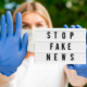 una dottoressa regge un cartello con la scritta stop fake news