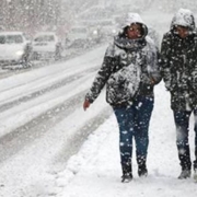 una donna e un uomo camminano sotto la neve al freddo indossando dei cappotti