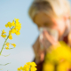 allergie: una donna si soffia il naso vicino a dei fiori