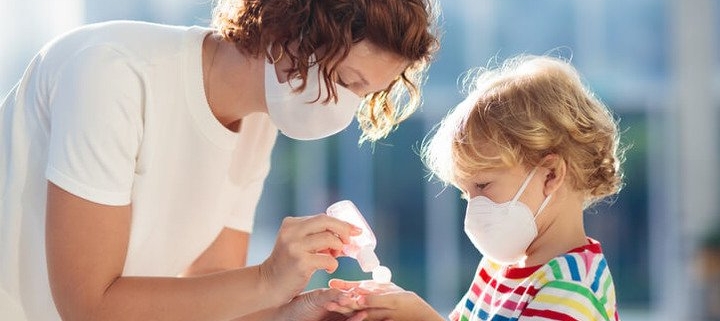 polmonite, una mamma mette del disinfettante sulle mani di un bambino