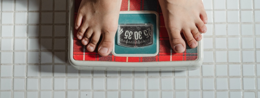 obesità, i piedi di un bimbo su una bilancia
