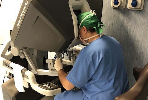 tumore del pancreas: un chirurgo seduto alla consolle del robot operatorio da vinci