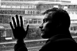 depressione e prevenzione del suicidio: un uomo in bianco e nero appoggiato al vetro