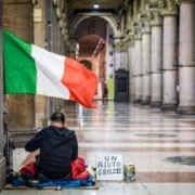 povertà a pasqua. uomo siede per terra sotto la bandiera italiana