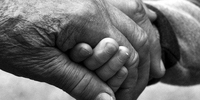 covid, la mano di un anziano tiene stretta quella di un bambino