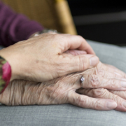paziente cronico, una mano caregiver su un'altra mano di un'anziana
