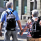 invecchiamento attivo, due anziani per mano camminano con zaino da viaggio
