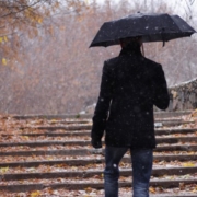 malanni di stagione. uomo con ombrello sale le scale piene di foglie