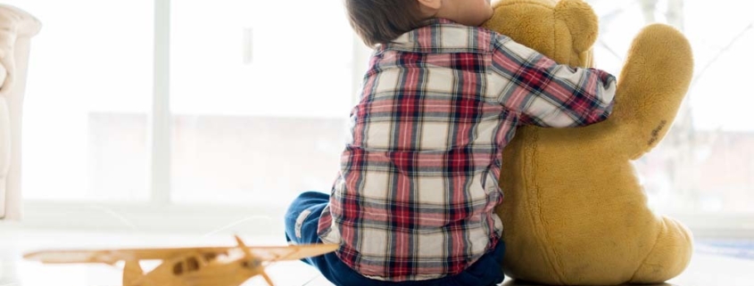 autismo: bimbo di spalle abbraccia un peluche