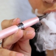 sigarette elettroniche: in primo piano una e-cig e una nuvola di fumo svapato dalla bocca di una persona
