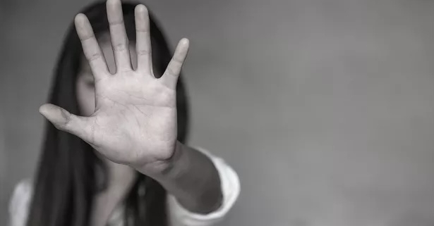 violenza, una donna in bianco e nero con il palmo della mano aperta in primo piano in segno di stop