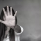 violenza, una donna in bianco e nero con il palmo della mano aperta in primo piano in segno di stop