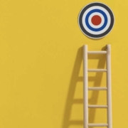 obiettivi, una scala su un muro giallo, con un bersaglio in cima