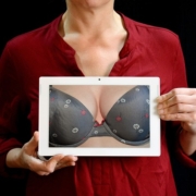 carcinoma mammario, una donna tiene in mano una foto nella quale si vede un seno fasciato nel reggiseno. il senso della foto è di parlare di prevenzione del tumore alla mammella