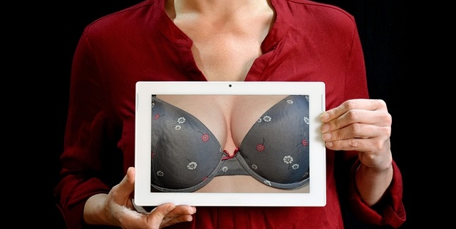 carcinoma mammario, una donna tiene in mano una foto nella quale si vede un seno fasciato nel reggiseno. il senso della foto è di parlare di prevenzione del tumore alla mammella