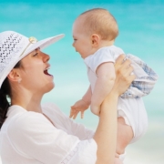 virus e batteri una mamma tiene in braccio il suo bambino sulla spiaggia.