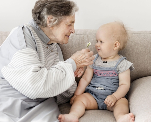 virus respiratorio sicinziale (rsv): donna anziana e un neonato sul divano sorridono giocando