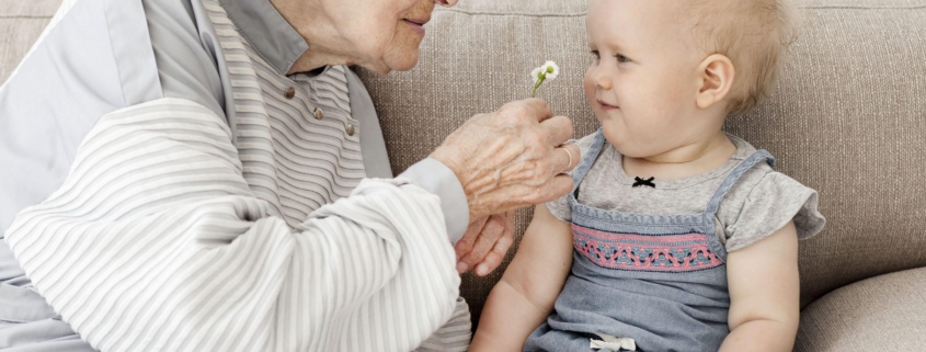 virus respiratorio sicinziale (rsv): donna anziana e un neonato sul divano sorridono giocando