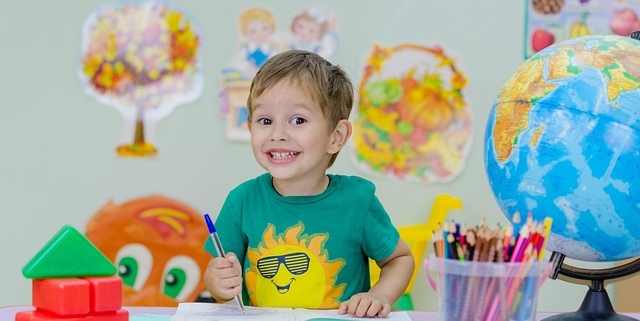 rientro a scuola un bimbo sorride mentre colora un disegno