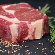 carne sintetica, una fetta di carne cruda con del sale e un rametto di rosmarino