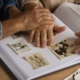 alzheimer, le mani di due anziani mentre sfogliano un album di foto in bianco e nero