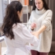 linfedema, una dottoressa visita il braccio di una donna giovane che indossa un maglione a collo alto