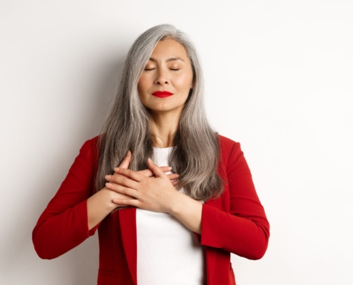 cuore e ictus, una donna con gli occhi chiusi tiene le mani sul cuore, ha i capelli bianchi lunghi