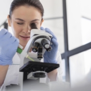 covid a woman looking through a microscope