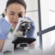 covid a woman looking through a microscope