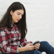 dipendenza, una donna seduta su una superficie bianca che guarda un cellulare