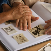 alzheimer, le mani di due anziani su un album dei ricordi