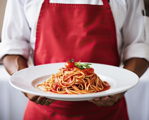 carboidrati, uno chef regge un piatto di pasta al sugo